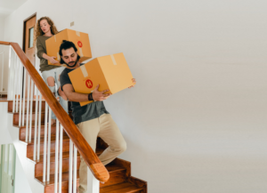 Couple with Moving Boxes Walking Down Stairs | Dallas Apartment Locators | Free Service | Call 972 818 3456