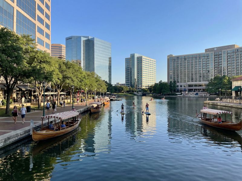 Waterway with boats and paddleboarders in city.