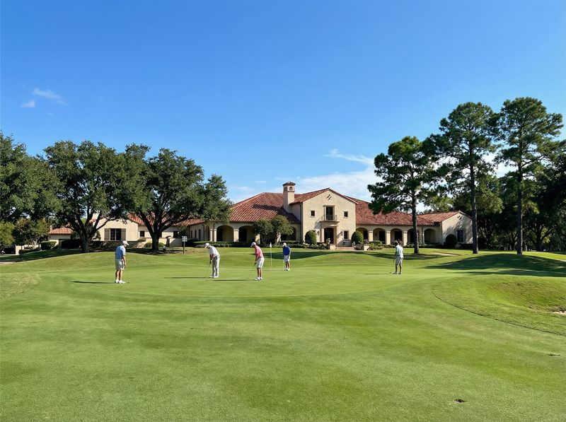 Golfers on green near clubhouse under blue sky