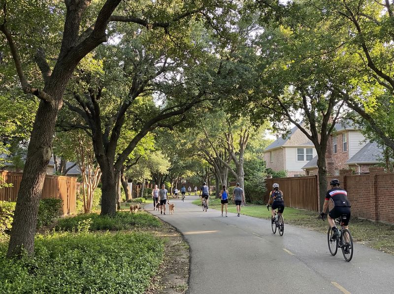 People walking and biking on shaded path.