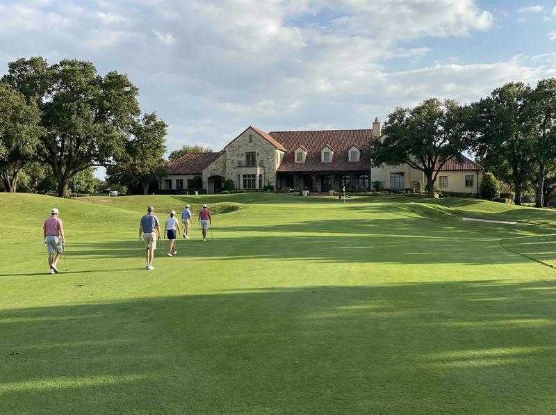 Golfers walking on lush fairway towards clubhouse.