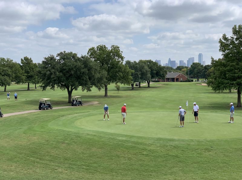 Golfers on a green with city skyline