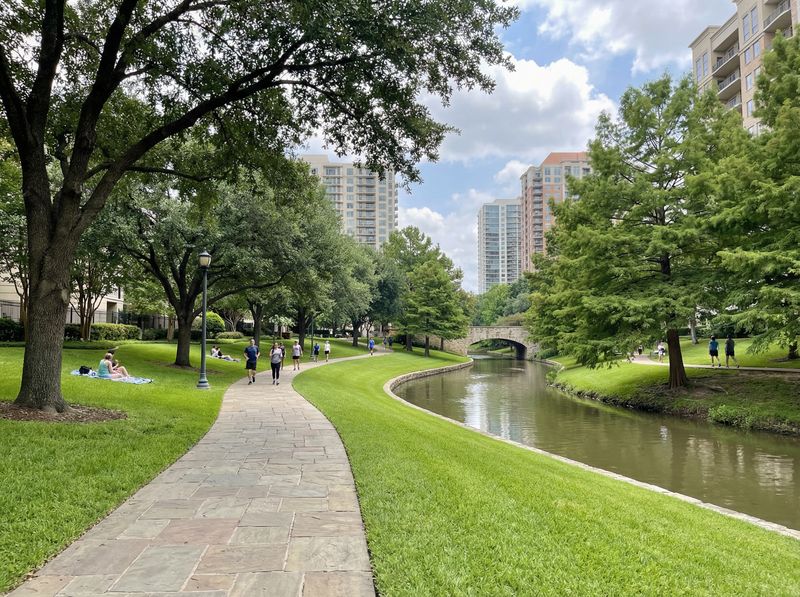 Park with path, trees, and river.